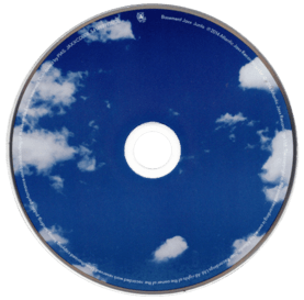 a cd of the album Junto by Basement Jaxx. it is a normal shaped cd with a blue bright sky design with many white clouds on it.